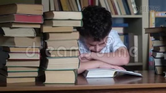 男孩坐在一张木桌旁，读一本厚厚的书。视频