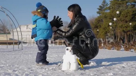 小男孩和他妈妈在雪地公园玩得很开心。 快乐的家庭在冬天玩雪。 活跃的冬季游戏。视频