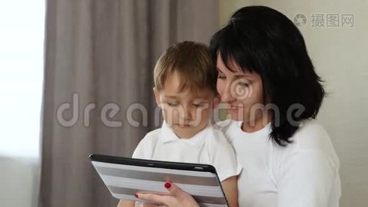 妈妈和她的孩子在家里玩平板电脑，玩和看动画片，玩电子游戏，使用视频
