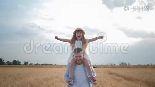 在田野里的家庭娱乐，快乐的年轻爸爸，肩上戴着草帽的小女孩，张开双手视频
