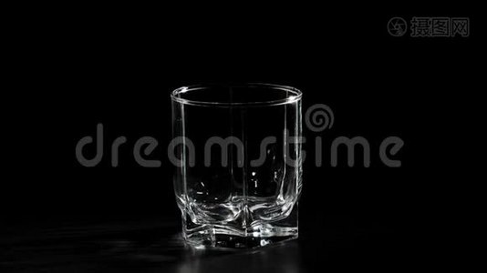 豪华威士忌。 空玻璃在黑色背景下旋转在黑色桌子上。 准备饮酒。 不倒翁威士忌。视频