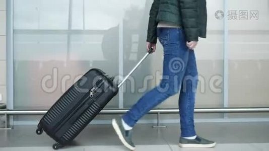 女人正走在现代机场航站楼里，提着手提箱，特写腿。视频