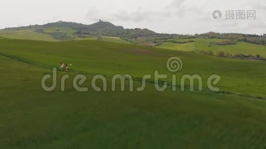 两个年轻的女人在绿色的田野上沿着小路奔跑。 意大利，托斯卡纳。视频