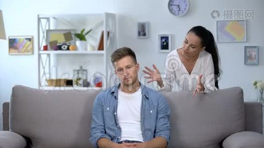 紧张的女人批评坐在沙发上的懒惰丈夫，家庭冲突，问题视频