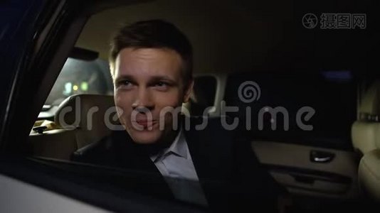 英俊的男演员从车后座看公众，欣赏电影首映式视频