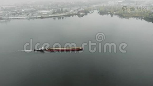 满载沙子的大型旧铁驳船正在烟雾中沿着工业市中心的河流航行。 煤在工业上漂浮在雾中视频