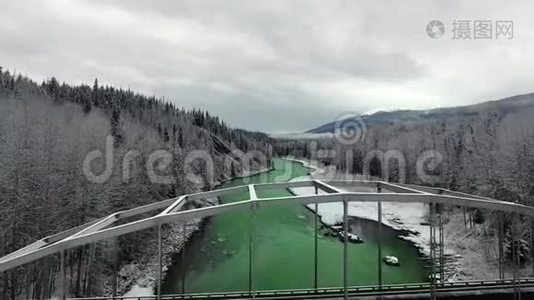 空中照相机在茂密的冬季松林中穿过一座桥，可以看到山景视频