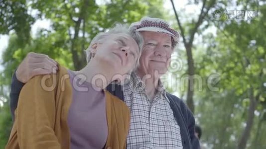 可爱的成熟情侣坐在公园的长凳上相爱的肖像。 可爱的女人和老人在一起。 投标视频