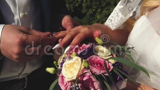 结婚典礼。 新郎和新娘在夏日公园的背景上互相戴上结婚戒指视频