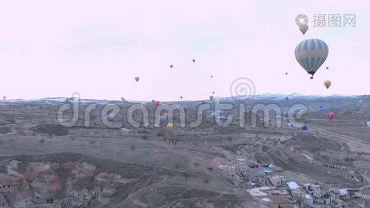 土耳其卡帕多西亚日出时，天空晴朗，天空中有许多热气球的空中山谷景观视频