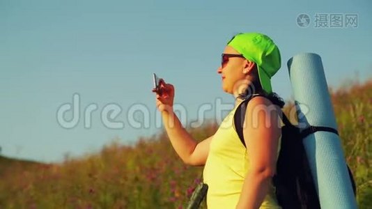 女徒步旅行者在山上背着背包，双筒望远镜自拍视频