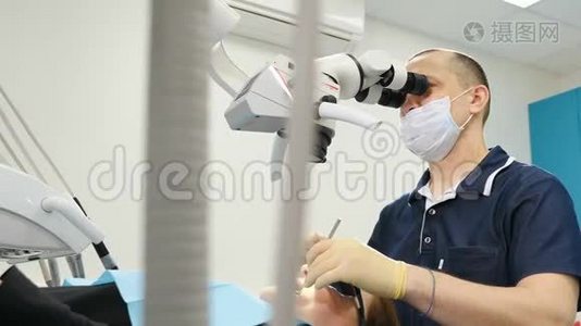 带有显微镜目镜的牙医。 牙医在现代牙科诊所治疗病人。 带牙具的男性牙医-视频
