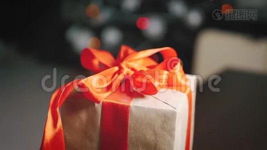 背景圣诞树上的棕色礼品盒和红色丝带。视频