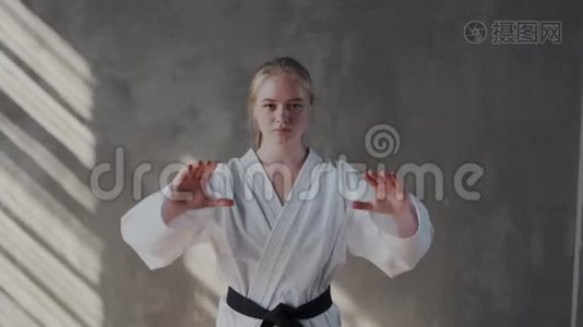 一个女孩表演传统的跆拳道姿势。 她的双臂张开，张开手掌，看着镜头视频