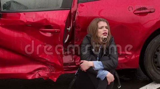 一个女孩坐在一辆破车附近的地上，她出了车祸视频