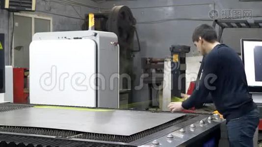 工程师在数控激光机床上调整切割金属板的铁片视频
