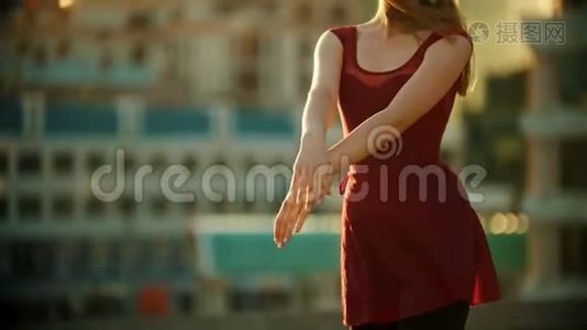 年轻漂亮的女芭蕾舞演员穿着红色的裙子站在屋顶上-用手跳舞-明亮的日落视频