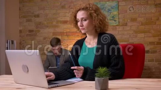 在办公室里用笔记本电脑工作的白种人成年女商人的特写镜头。 商人处理她视频