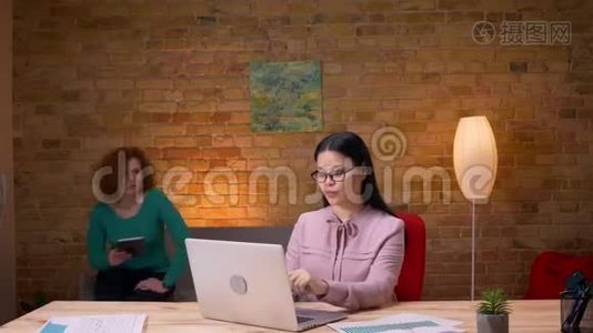 在办公室室内工作的成人亚洲女商人的特写镜头。 男性雇员带她来视频