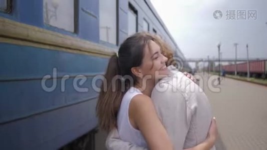 幸福的年轻女子拥抱男人，分离后在火车站的火车车厢旁欢笑视频