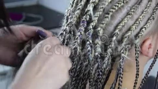 理发师的手在金发女孩的头上做辫子特写视频