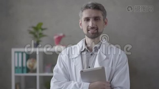 英俊的技巧，微笑的男人，穿着白色长袍，看着相机拿着平板电脑。 现代成人医生视频