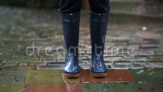 穿着深蓝色雨靴的人在后院、城市街道或公园铺好的道路上行进视频