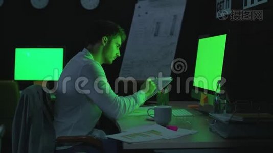 专注于工作的商人在夜间办公室的绿色屏幕前工作视频