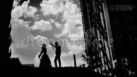 两个相爱的人在美丽的天空上跳舞的黑白剪影。视频