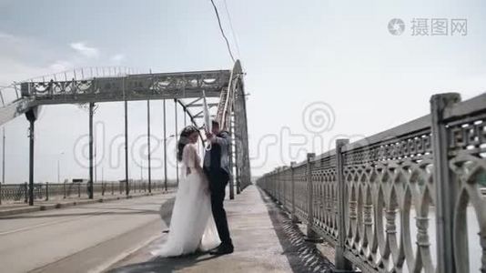 疯狂的一对新婚夫妇手里拿着伞在桥边跳舞。视频