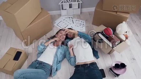 幸福的夫妻在新公寓里躺在地板上，在搬家过程中交谈和环顾四周视频