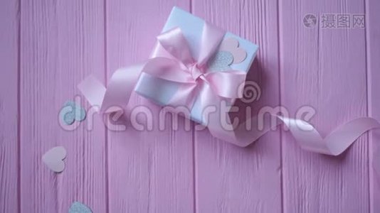 礼品盒与丝带和纸屑的形式，心在粉红色的木制背景与地方为您的文字。 录像播放视频