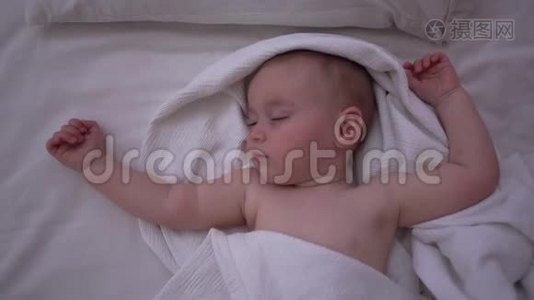 一个蹒跚学步的孩子睡在大床上，双手抬起，动作缓慢视频