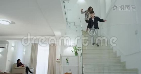 在一个现代化的房子里，有一个大的生活和白色的楼梯，两个孩子早上跑到一楼去。视频