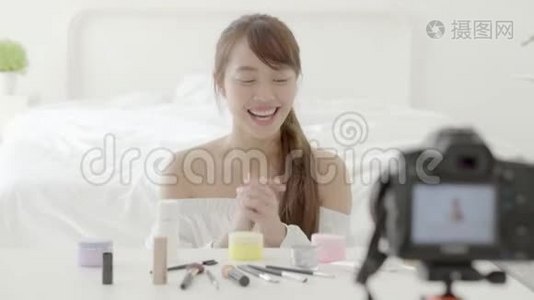 美丽的亚洲年轻女性，在家里用视频和vlog显示化妆霜或化妆水视频