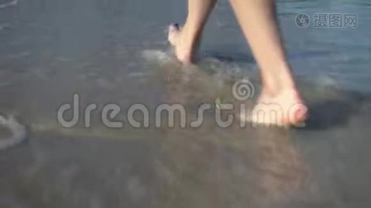 一个女人在沙滩上散步。 双腿合拢。 海浪涌到海边视频