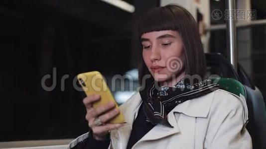 吸引人的年轻女性在公共交通上的智能手机上观看视频。 晚上。 特写镜头。 城市灯光视频