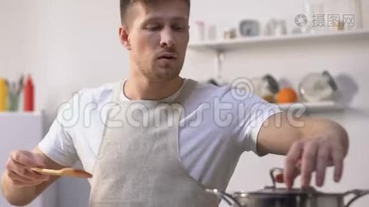 穿着围裙做饭的帅哥，在平底锅里搅拌食材，尝试着吃饭视频