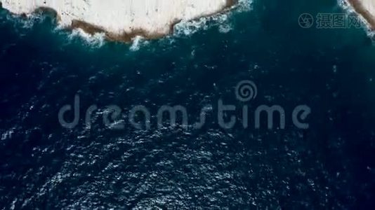 从空中无人机拍摄的海浪冲击到岩石海岸线的俯视图视频