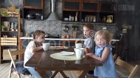 家庭晚餐：三个孩子在厨房的桌子上吃面包和喝茶。视频