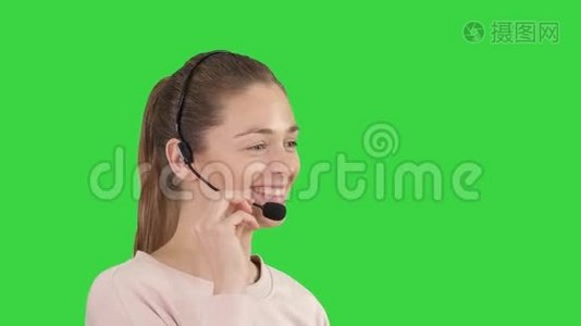 美丽的呼叫中心操作员与耳机交谈在绿色屏幕，色度键。视频