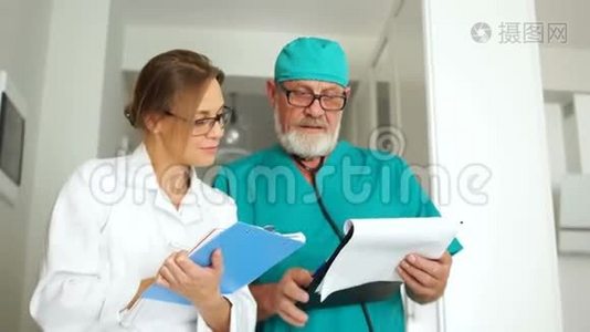 两位医生，一男一女，正在诊所的走廊里交谈。 国际医生日，医学和视频