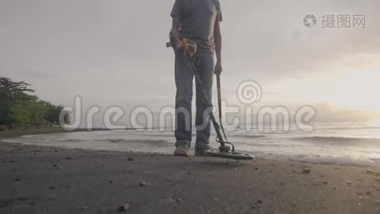 无法辨认的人带着电子金属探测器，带着他的狗在海洋热带沙滩上搜寻宝藏视频