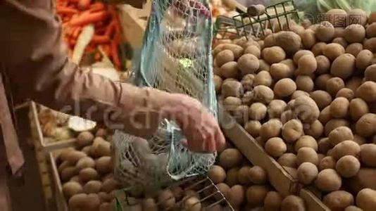 特写女性用手从绿色杂货店的木箱里用一个细绳袋采摘土豆。 环保包装，零废物视频