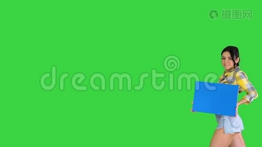 年轻迷人的黑发模特拿着空板在绿色屏幕，蓝色模型。视频