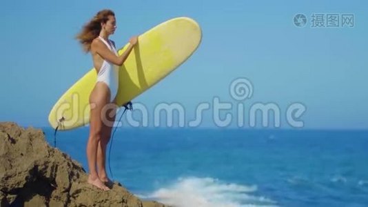 美丽的女人穿着比基尼和冲浪板在海滩上散步，性感的冲浪女孩在海滩上。 健康观念视频