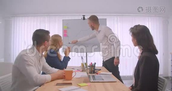四个欢快的拼贴画在办公室室内开会。 商人在白板上画一张图表视频
