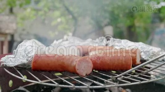 烧烤，烤香肠和肉，在野餐会上用箔纸烤煤视频