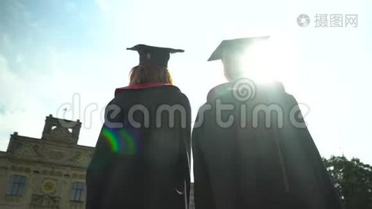 后景两名学生在壁炉前庆祝他们的毕业在大学大楼前。 毕业，新生活视频