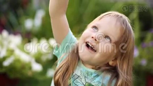 超级可爱的金发小女孩穿着t恤在草地上吹肥皂泡。视频